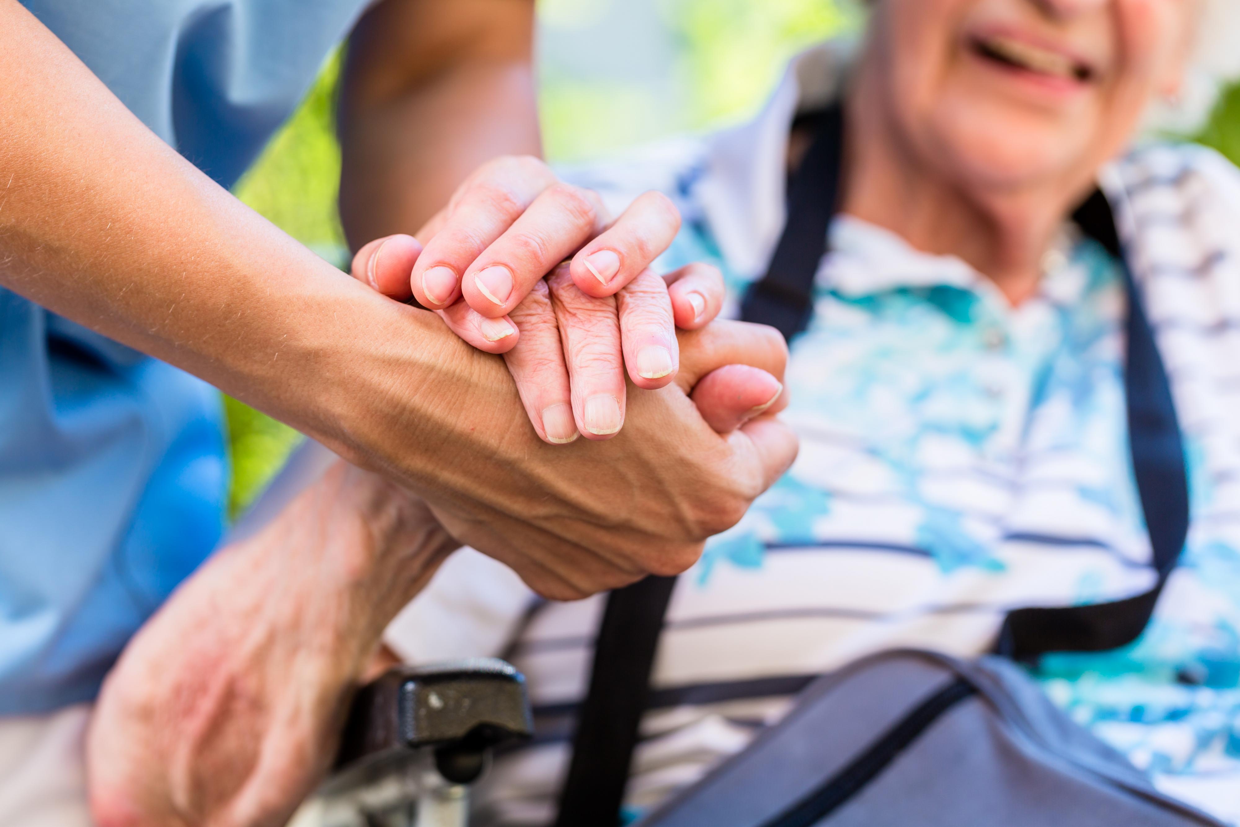 young person holding the hands of older person