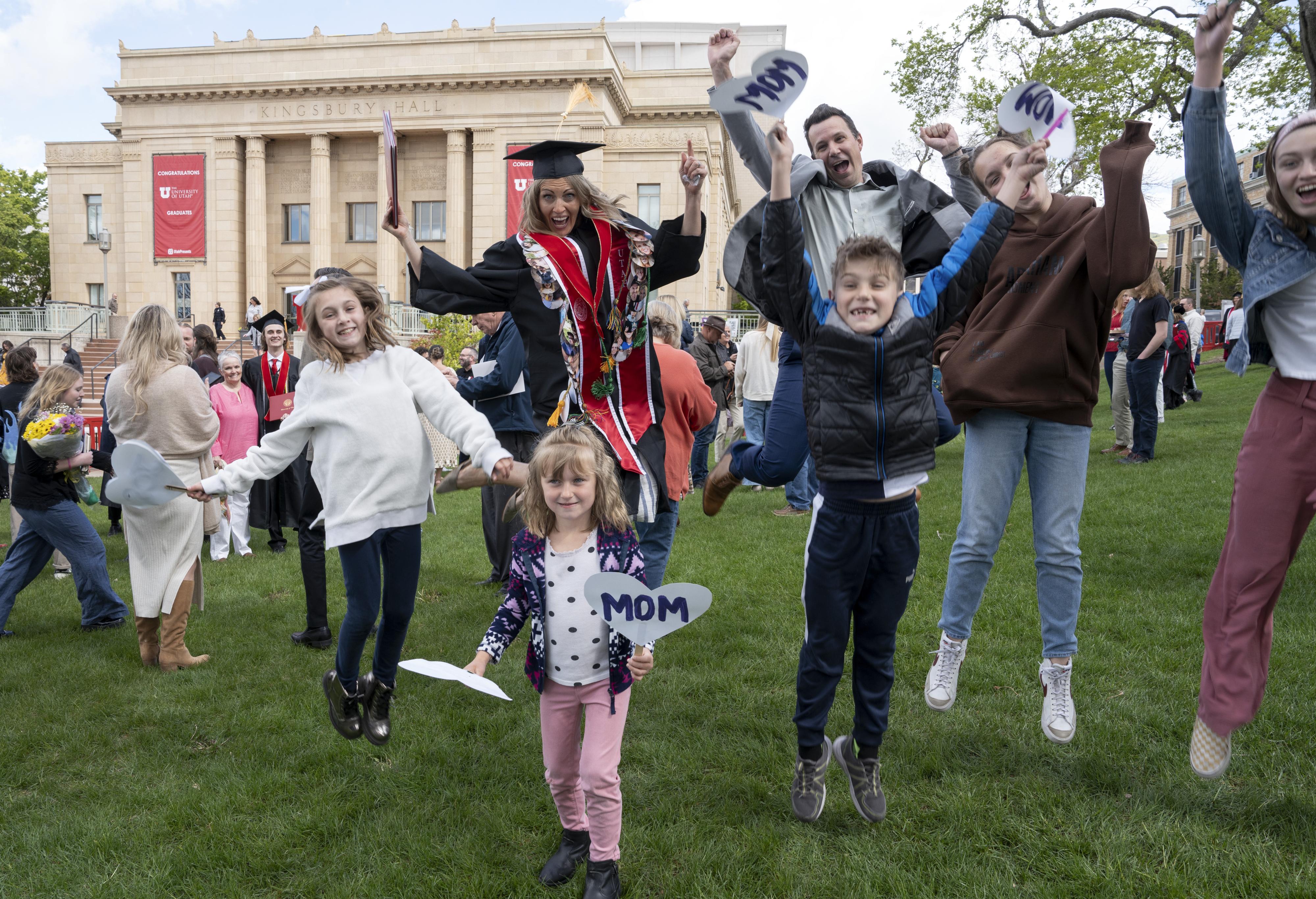 A graduate jumps in celebration with family members