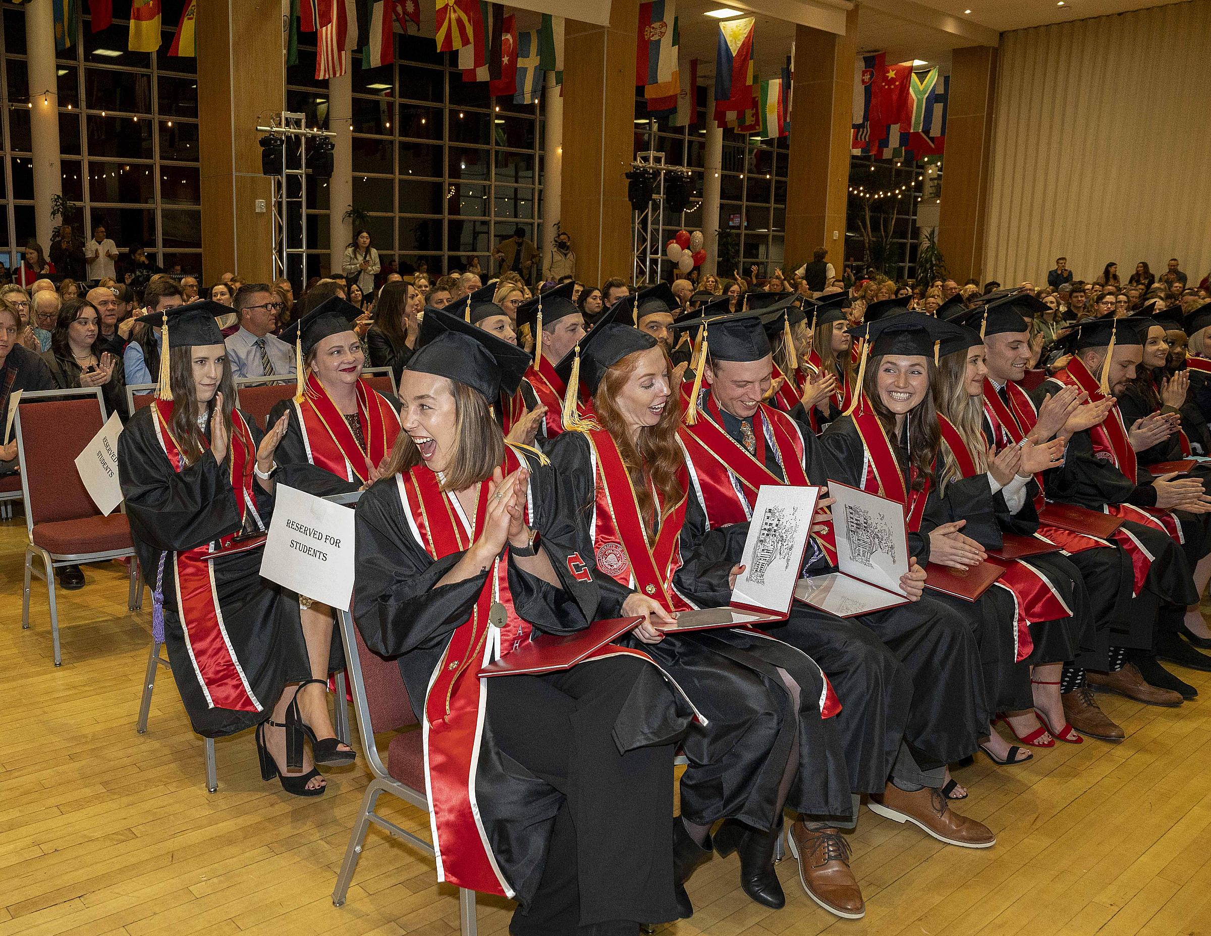 Graduates sitting in a row wearing black and red regalia