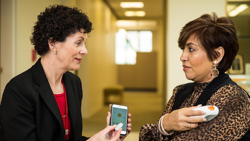Nancy Allen holds an iPhone and speaks with an individual 